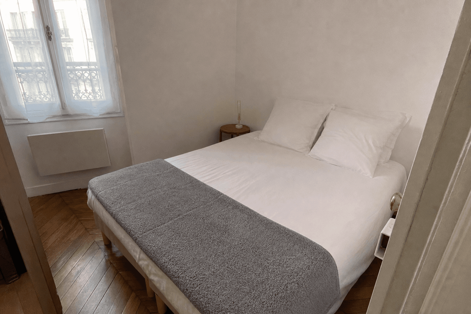 Lit double fait, draps blancs, dans une chambre parisienne